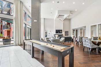 A billiard table is in the middle of a spacious room with a balcony outside.